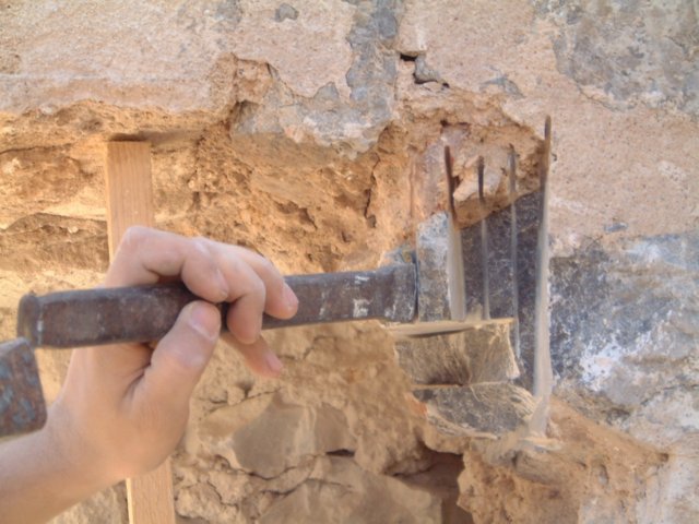 Herramienta manual junto a una zona picada de un muro