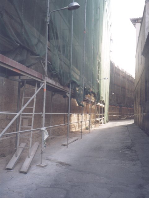 Andamio cubierto con malla junto a una calle estrecha