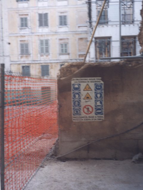 Señales de seguridad junto a malla y muro de obra