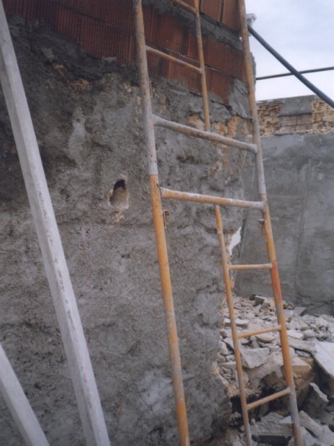 Escalera apoyada junto a un muro parcialmente desmontado