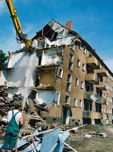Demolición de edificio con máquina y persona en primer plano