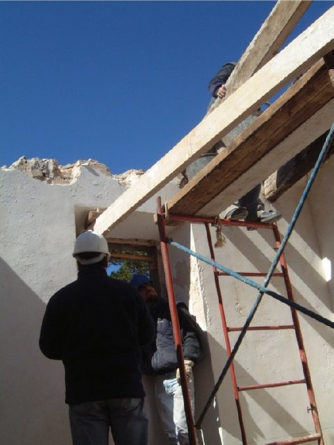 Trabajador sobre andamio junto a un muro parcialmente demolido