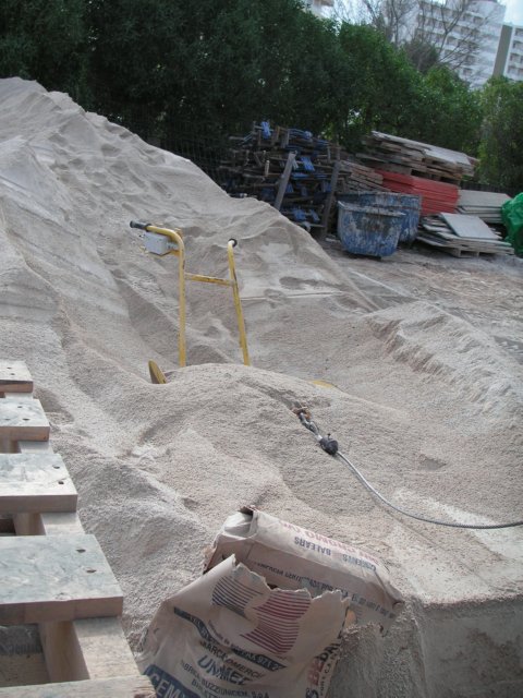 Montón de arena, herramientas y cables en una zona de acopio